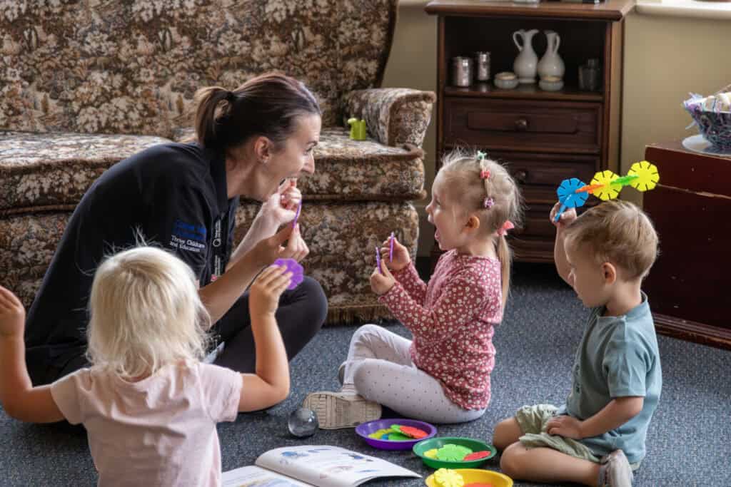 Bright, caring childminder engaging with young children during educational play in a welcoming childcare setting. Focus on early childhood development and nurturing care at Thrive Childcare.