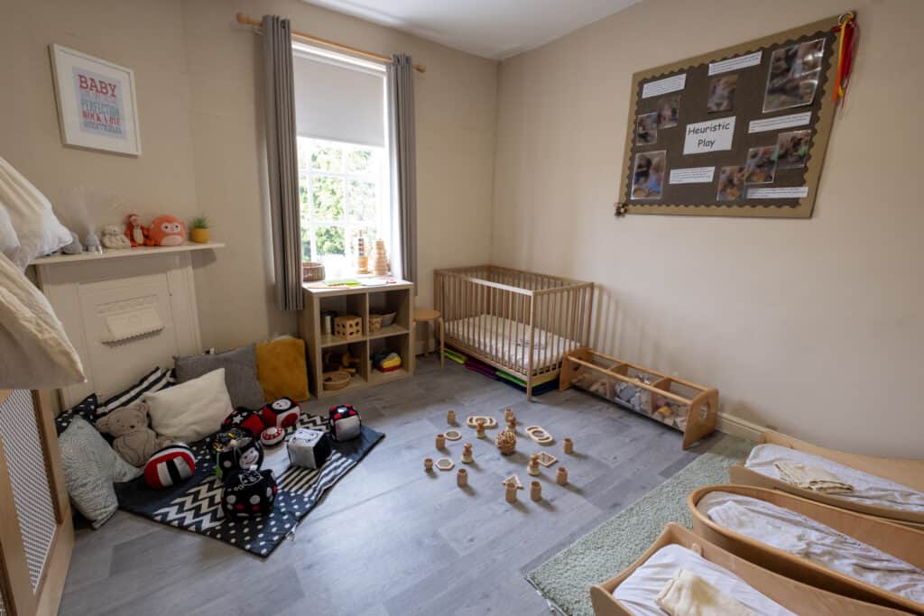 Bright, welcoming children’s playroom at Thrive Childcare featuring soft toys, wooden activity toys, a cosy corner, and a crib area, perfect for infant and toddler development and imaginative play.