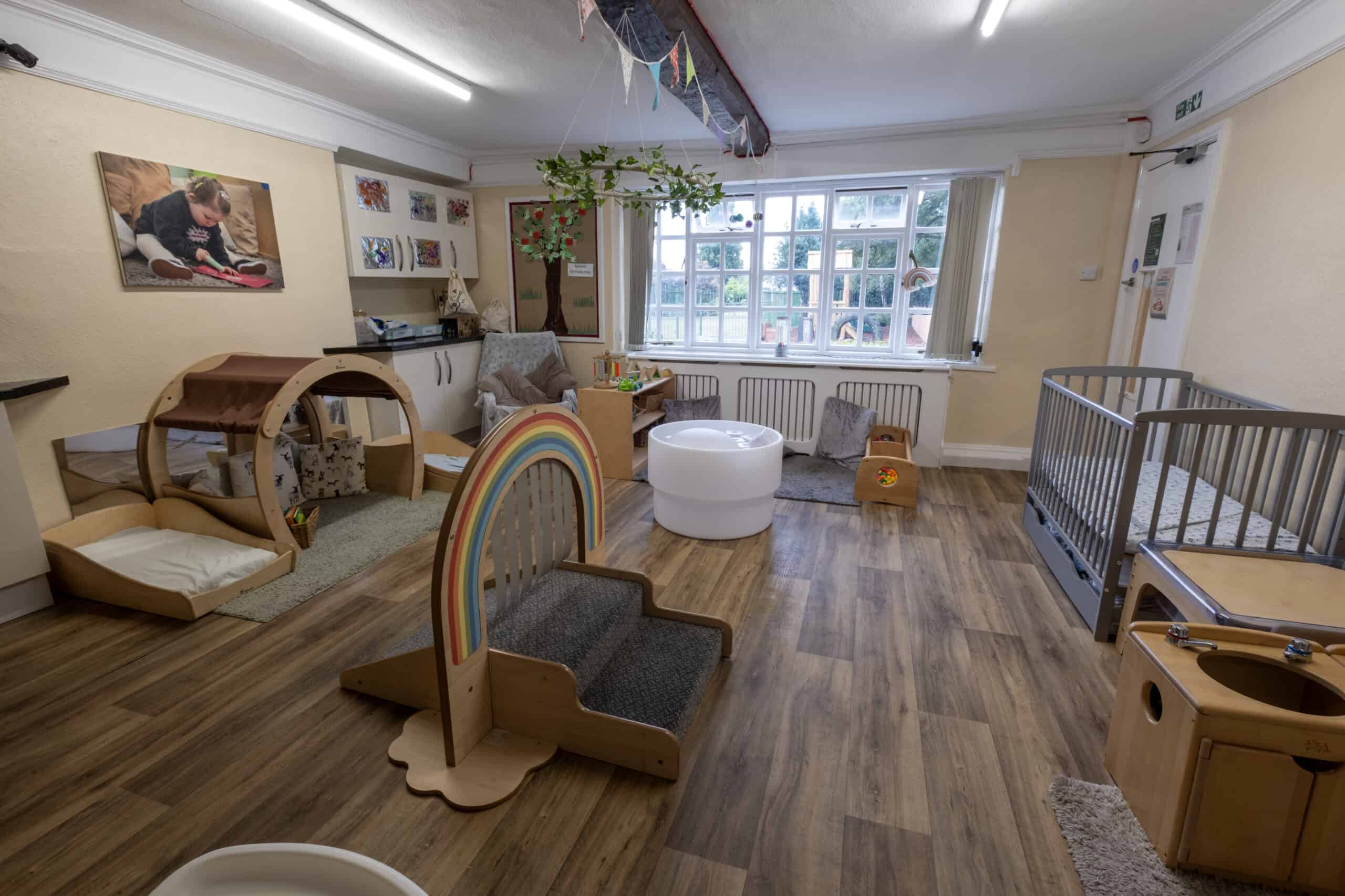 Bright and welcoming childcare room at Thrive Childcare, featuring safe cribs, interactive play areas, and engaging toys for early childhood development. Ideal for nurturing and learning.