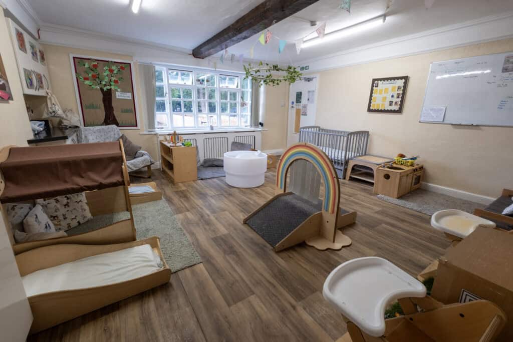 Bright and welcoming childcare indoor play area with wooden furniture, toys, and colourful decorations at Thrive Childcare.