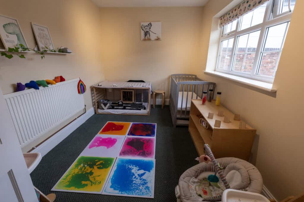 Bright and welcoming nursery room at Thrive Childcare with soft natural lighting, suitable for early childhood education and play activities, featuring baby cribs, sensory toys, and colourful artwork for young children.