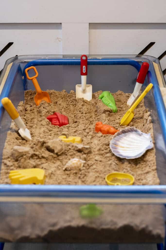 Sandtray with children's toys and tools, suitable for early childhood development and sensory play at Thrive Childcare.