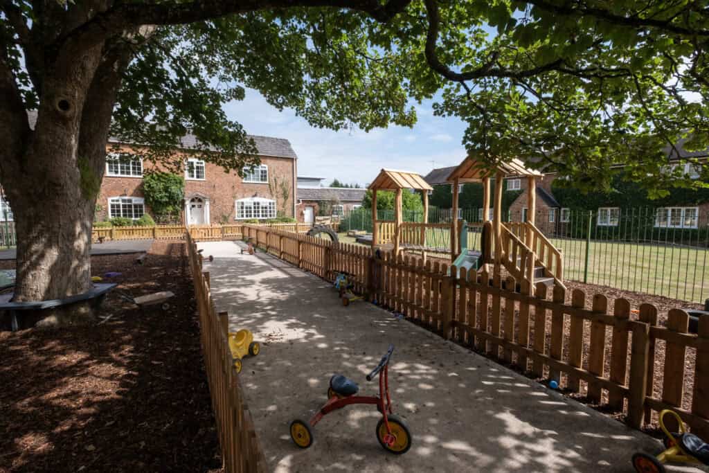 Bright outdoor play area at Thrive Childcare with safe fencing, wooden play structures, and toys, perfect for children’s outdoor activities and early childhood development.
