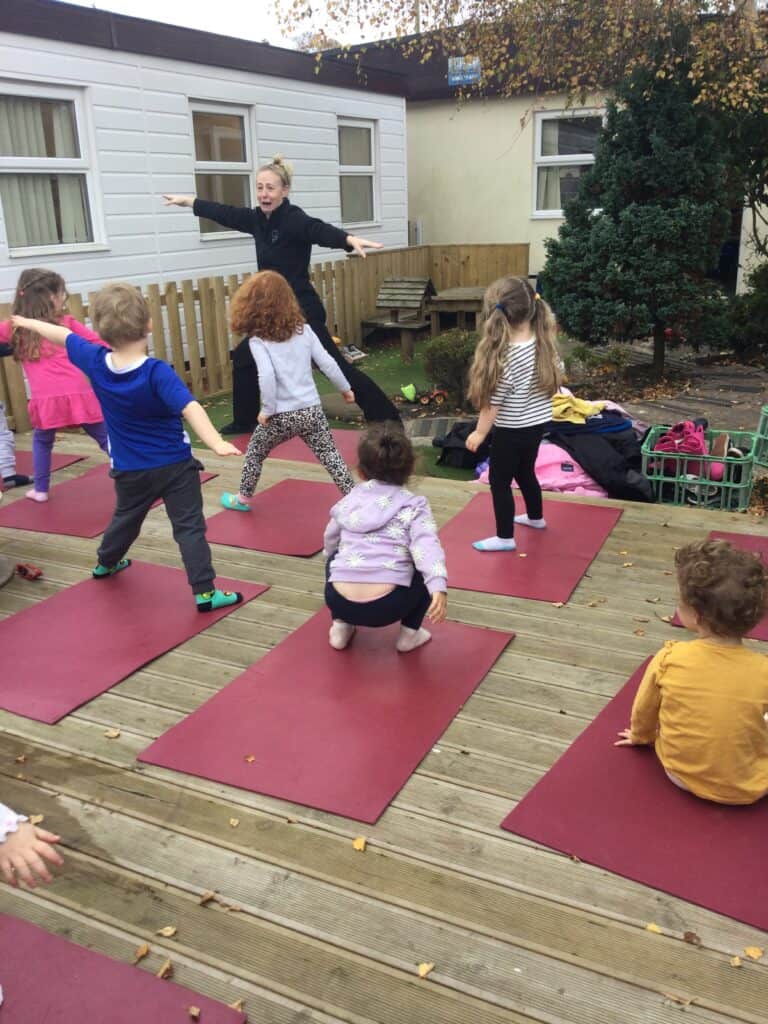 Children's outdoor yoga session at Thrive Childcare centre in a garden setting with an instructor guiding kids in exercise activities.