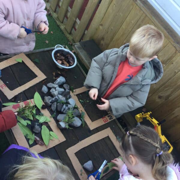 Bright preschool children engaging in outdoor nature activities at Thrive Childcare, exploring rocks, leaves, and plants in a safe, nurturing environment promoting early childhood education and development.