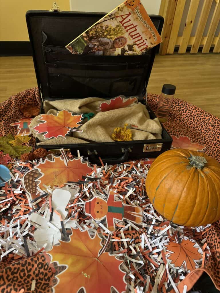 Colourful autumn-themed educational display with paper leaves, a pumpkin, and themed props for preschool learning and seasonal activities at Thrive Childcare.