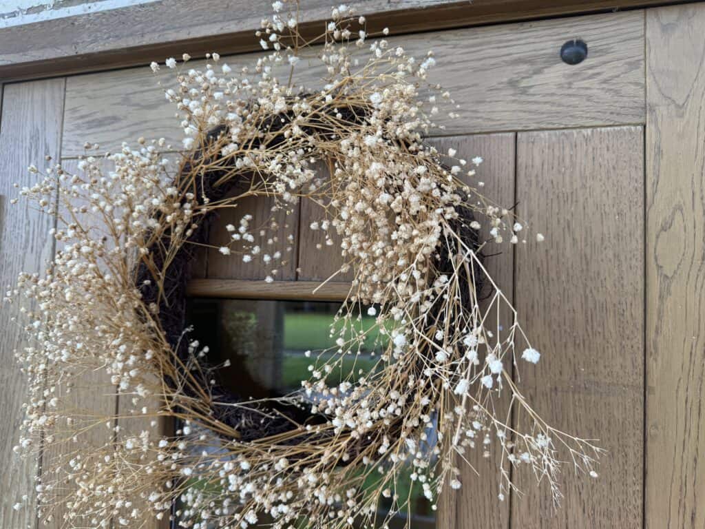 Miniature dried flower wreath hanging on a wooden gate, symbolising nurturing and care in early childhood, ideal for illustrating Thrive Childcare’s welcoming environment and focus on infant development and family engagement.