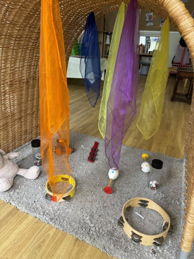 Colourful fabric streamers hanging from a wicker structure at Thrive Childcare, creating a playful sensory corner for children to explore and enjoy.