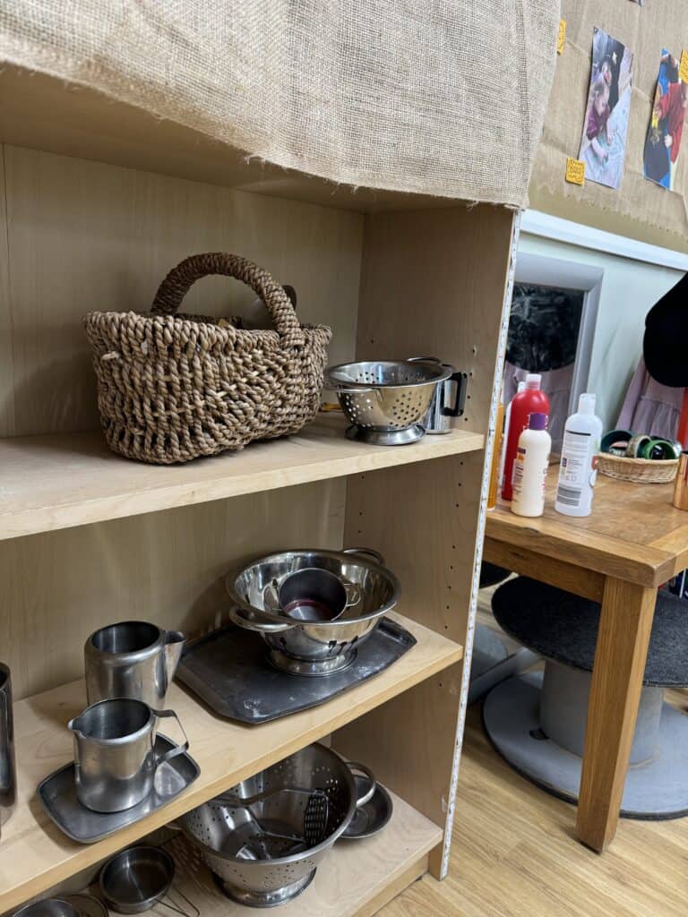Bright and inviting toddler kitchen play area at Thrive Childcare, promoting imaginative play and fine motor skills with stainless steel pots, pans, and accessories for early childhood development.