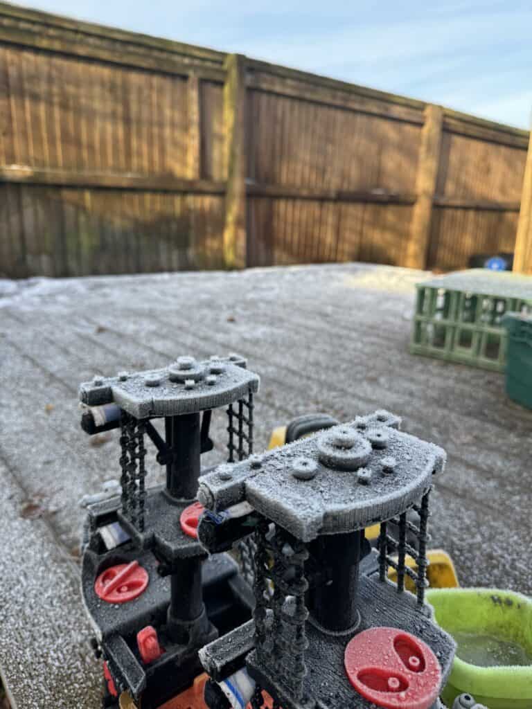 Frosted children's outdoor play equipment at Thrive Childcare, showcasing safe, winter-ready outdoor play area with snow and wooden fencing for secure childcare environment.