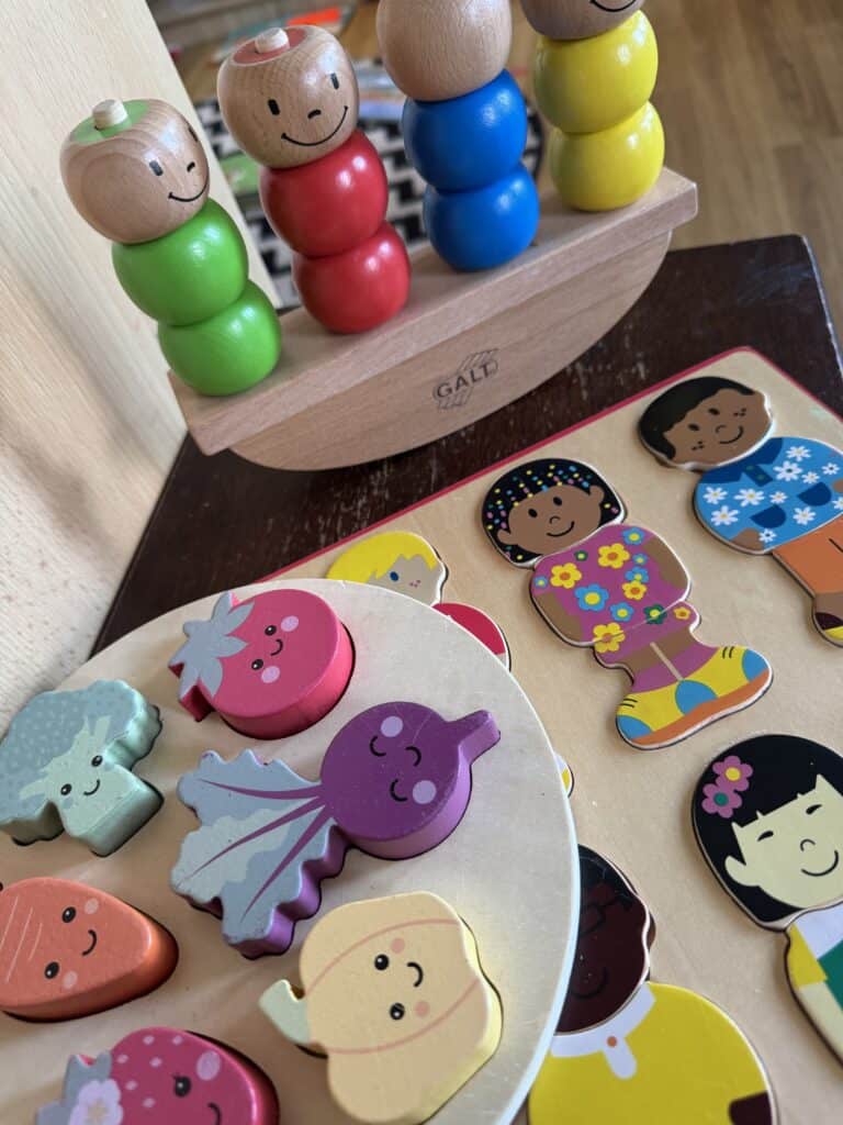 1. Colourful wooden stacking toy with smiling faces, perfect for early childhood development and play-based learning at Thrive Childcare.