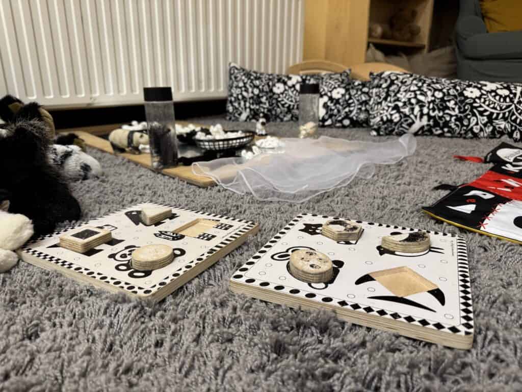 Wooden sensory and educational toys on a grey carpet, with soft toys and blankets in the background, creating a welcoming environment for early childhood development at Thrive Childcare.