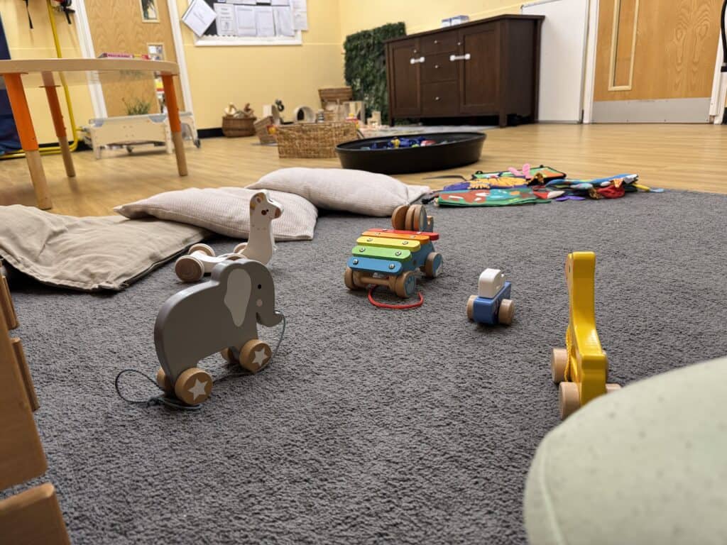 Soft play area with wooden toys, cushions, and quiet space inside Thrive Childcare, fostering a safe environment for children's early learning and development.