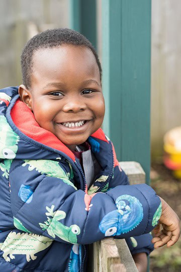 Bright smiling young boy at Thrive Childcare centre, enjoying outdoor activities in a nurturing early childhood education environment in the UK.