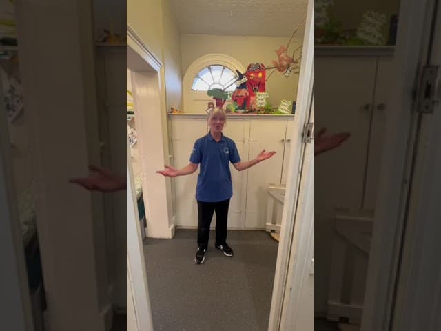 Friendly childcare staff member welcoming children at Thrive Childcare nursery in a warm, colourfully decorated environment.