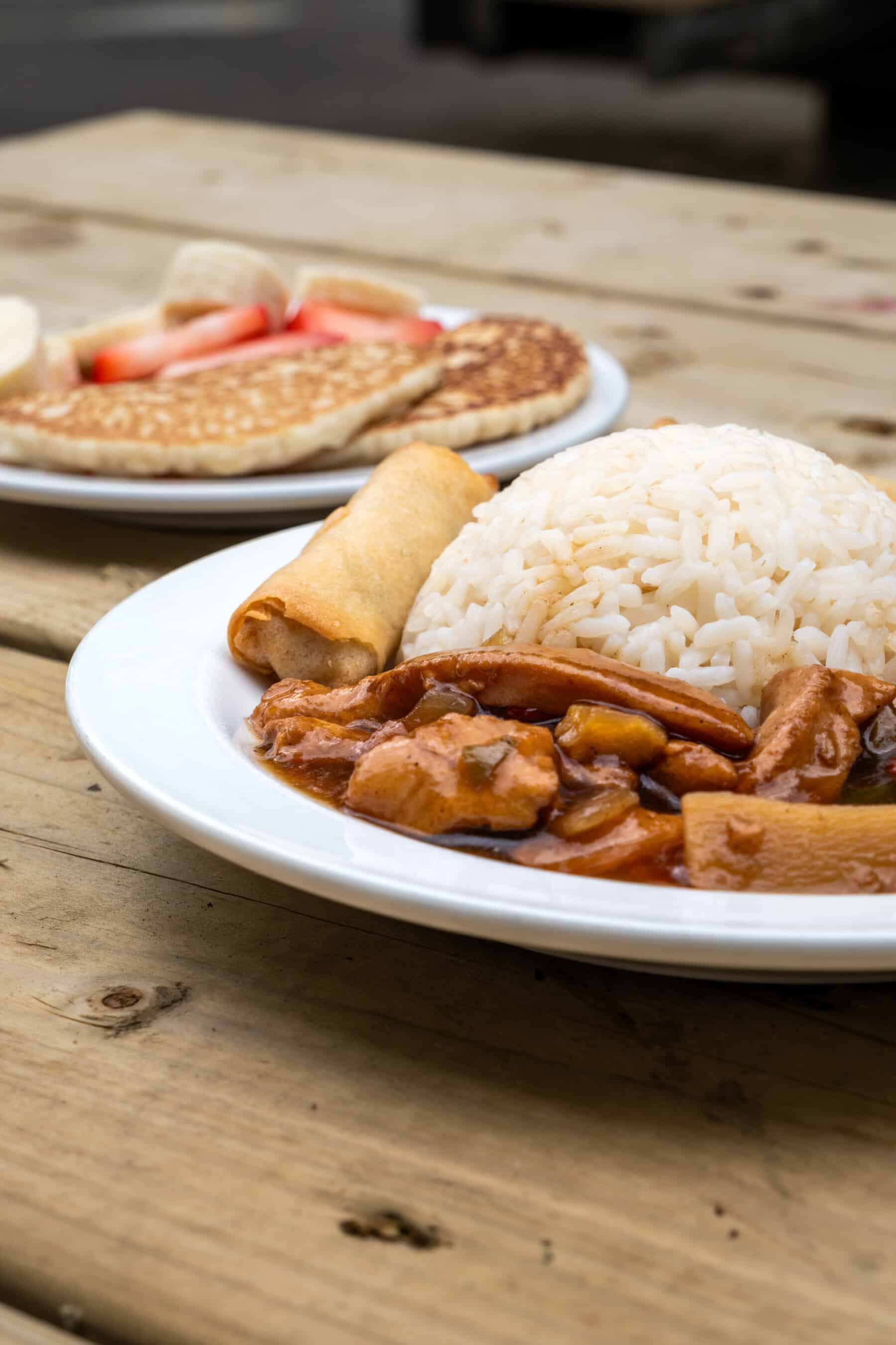 1. Delicious rice and chicken stir-fry served with spring rolls on a wooden table, highlighting nutritious meal options at Thrive Childcare.
