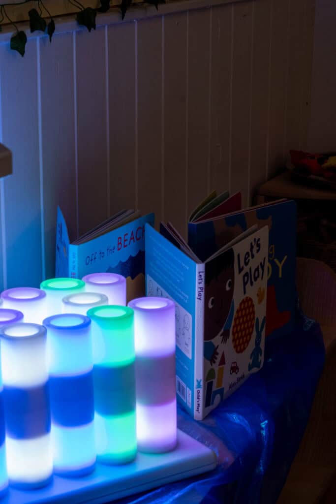 Bright colourful toddler books and illuminated sensory lights in a cosy nursery or playroom environment at Thrive Childcare, creating a stimulating and calming space for young children.