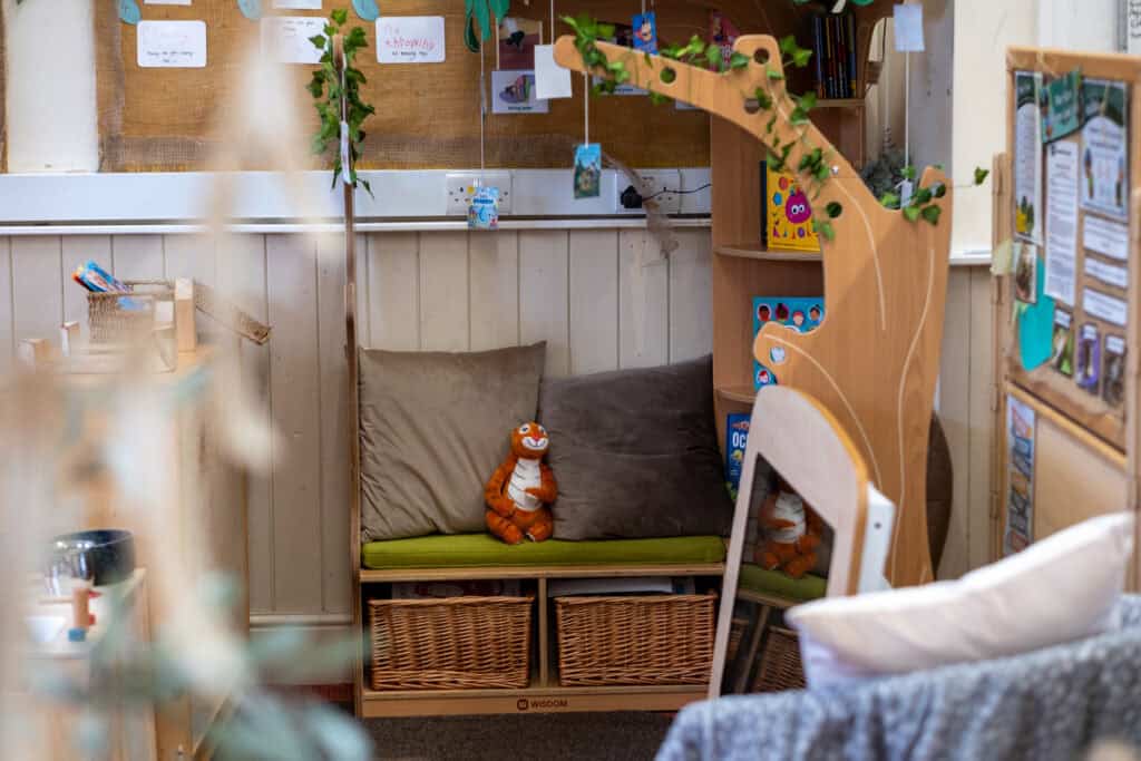 Comfortable childcare nap area with cushions and a plush tiger toy, featuring soft seating and organised storage, for safe and nurturing early childhood education.