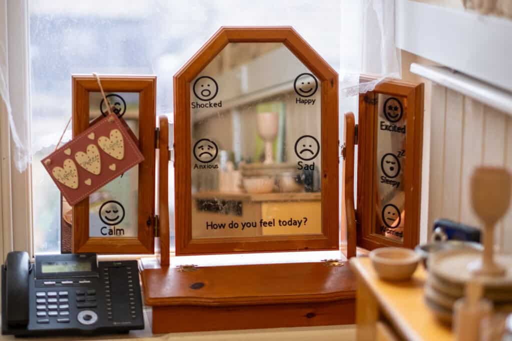 A cheerful mood board with smiley faces displaying emotions like happy, sad, angry, and calm, encouraging children to express feelings at Thrive Childcare.