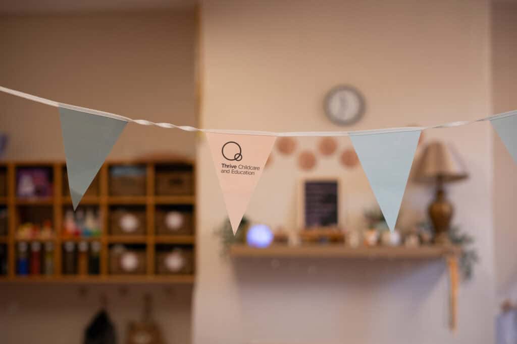 Brightly coloured Thrive Childcare and Education bunting hanging in a cozy, welcoming nursery or preschool environment, promoting early childhood development and quality childcare services.
