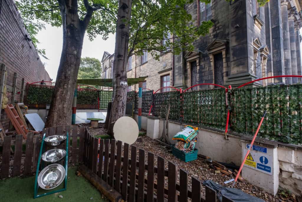 Bright outdoor play area at Thrive Childcare with trees, fencing, and playful elements for children’s outdoor activities and exploration.