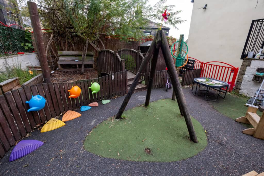 Colorful outdoor children's playground with climbing area, sandbox, and swings at Thrive Childcare. Safe and stimulating environment for early childhood development and playtime.