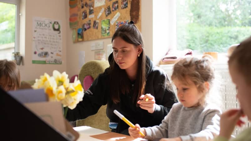 1. caring childcare professional engaging with young children in a supportive learning environment at Thrive Childcare in the UK.