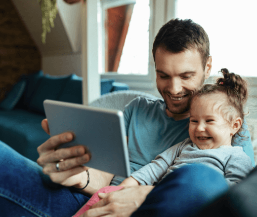 A joyful father and daughter enjoying storytime together on a tablet at home.