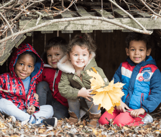Bright young children enjoying outdoor play under a wooden shelter at Thrive Childcare, promoting early childhood development, outdoor activities, and a safe learning environment in the UK.