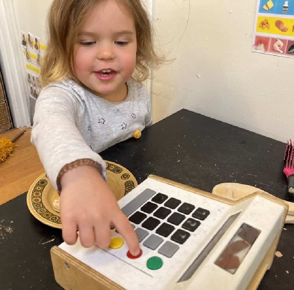Engaging young child playing with educational toy cash register at Thrive Childcare, promoting early learning and development in a nurturing environment.