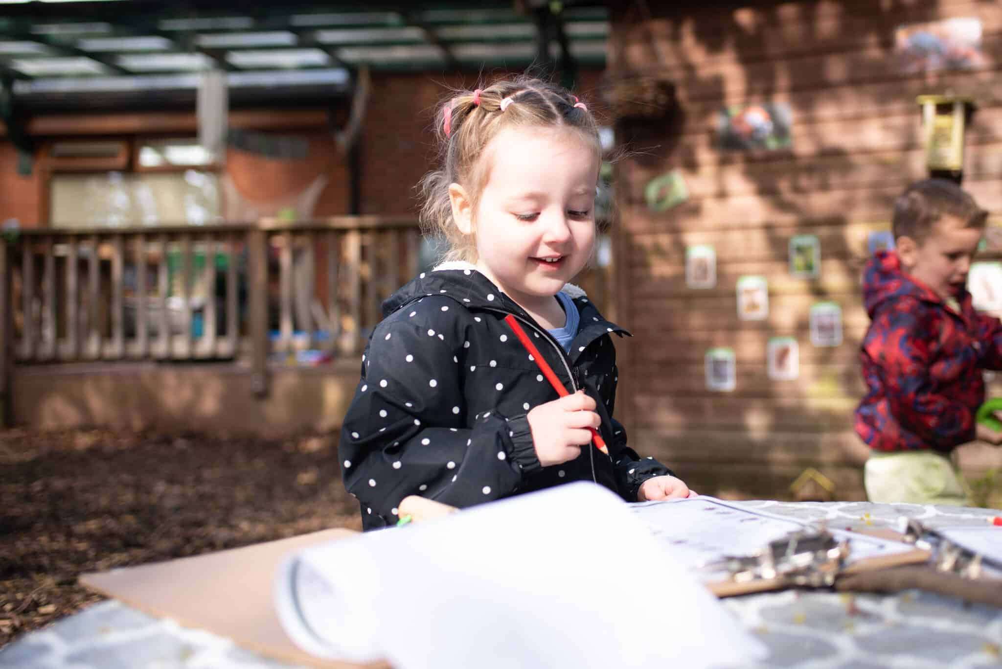 Young girl engaging in outdoor creative activities at Thrive Childcare outdoor play area, fostering early childhood development and imagination.