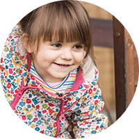 Bright smiling young girl playing outdoors at Thrive Childcare, highlighting nurturing early childhood education and outdoor activities for young children.