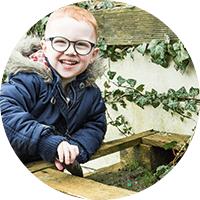 Bright-eyed young boy smiling outdoors at Thrive Childcare, showcasing happy children’s early education and play activities in a caring environment.