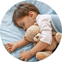 Soft-focused image of a young child sleeping peacefully with a teddy bear, highlighting safe and caring childcare environments.