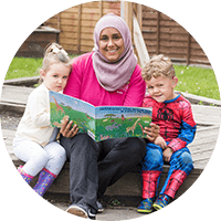 A joyful teacher reading a colourful storybook with diverse children outdoors at Thrive Childcare, promoting early childhood education, play-based learning, and nurturing care.