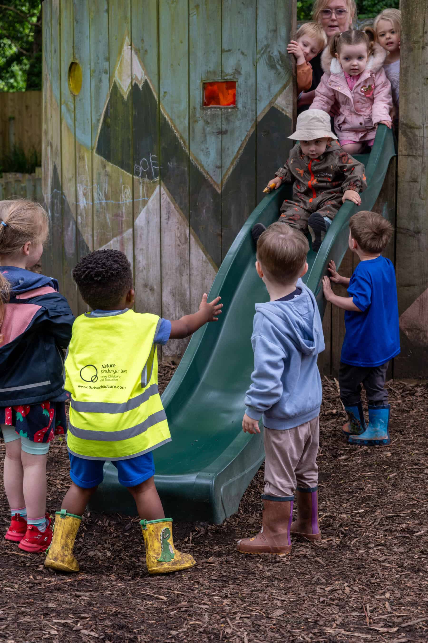 Children playing on a slide at Thrive Childcare outdoor playground, enjoying supervised fun and outdoor learning for early childhood development, with caring staff and safe environment.