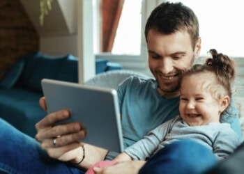 Engaging father and daughter enjoying quality time with a tablet at home, promoting early childhood development and family bonding in a nurturing environment.