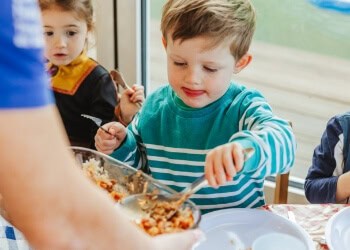Happy young boy enjoying a nutritious meal at Thrive Childcare, fostering healthy eating habits and social interaction for early childhood development.