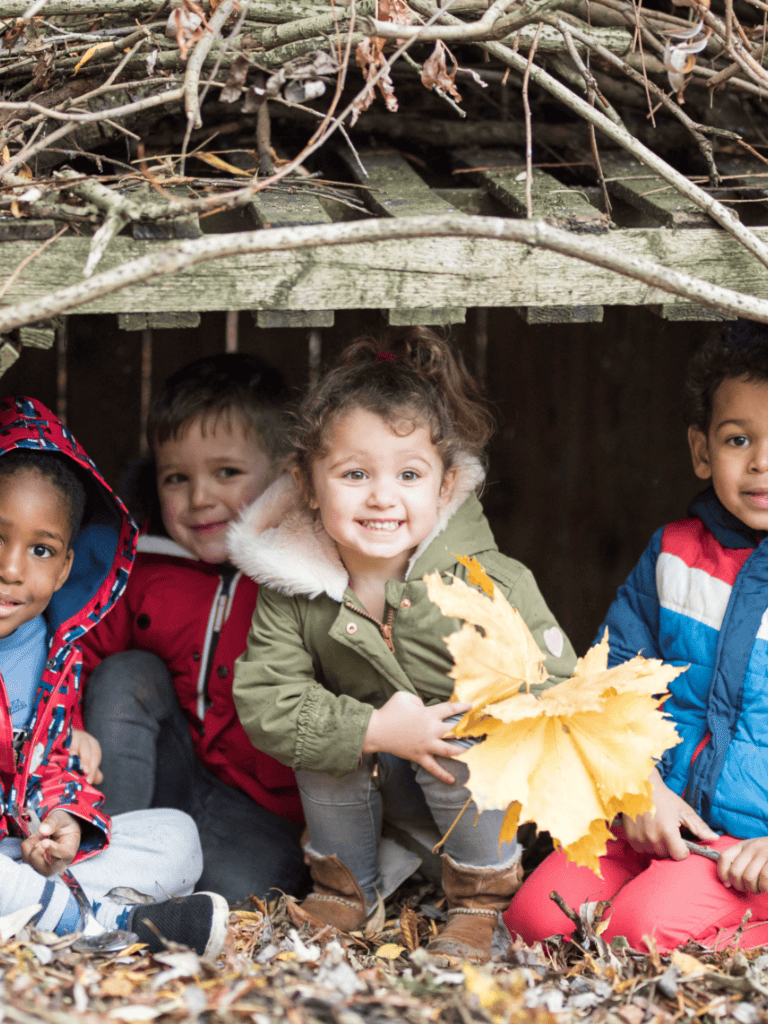 Bright smiling children playing outdoors in autumn leaves at Thrive Childcare, fostering early childhood development and outdoor learning in a safe, nurturing environment.