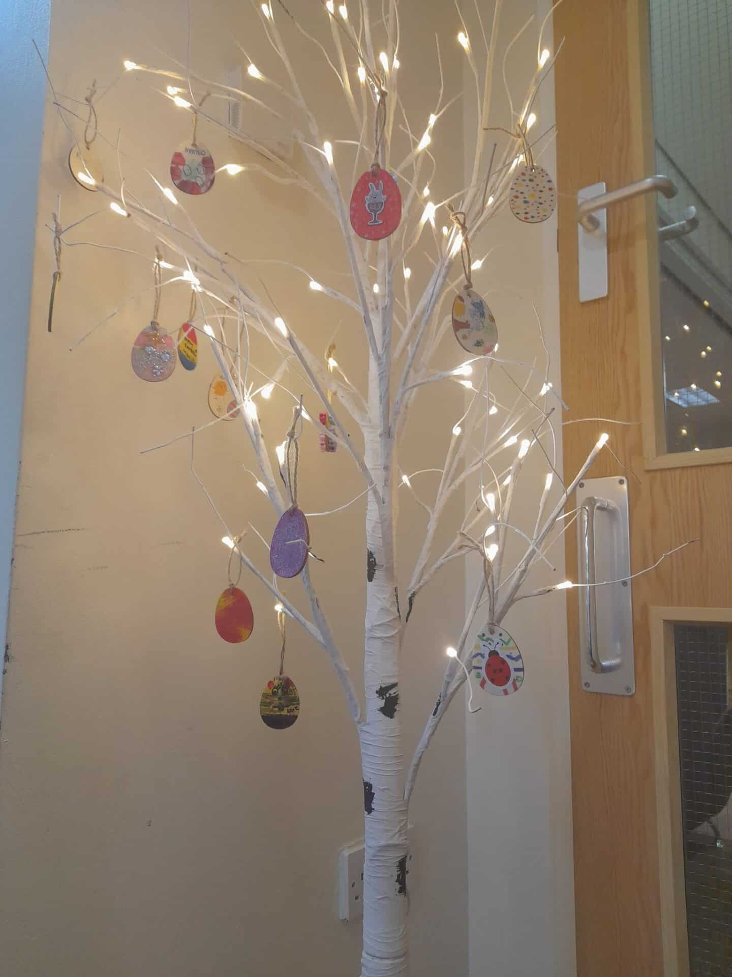 Brightly decorated Easter-themed illuminated tree with hanging ornaments inside a childcare centre, creating a festive and welcoming environment for children.