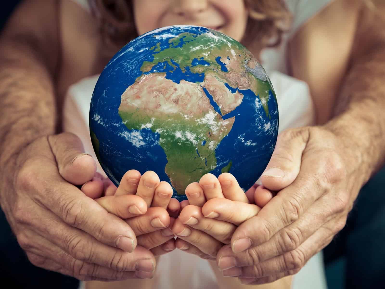 A child and an elderly person holding a realistic Earth globe together, symbolising care for the planet and environmental awareness.