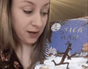 A young woman reading a children's book titled "Stitch Man" at Thrive Childcare, showcasing engaging early childhood literacy activities in a welcoming childcare environment.