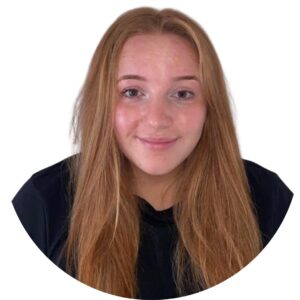 Friendly childcare professional with red hair, showcasing a welcoming smile, exemplifying caring and attentive staff at Thrive Childcare in a safe and nurturing learning environment.