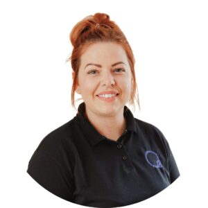 Friendly childcare provider with red hair and black Thrive Childcare uniform, smiling, representing quality early years education and caring staff at Thrive Childcare.