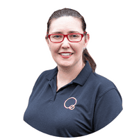 Bright-eyed childcare professional in navy uniform with Thrive Childcare logo, smiling warmly in a welcoming educational environment.