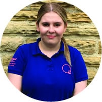 Bright young girl smiling in a blue Thrive Childcare uniform, outdoor background, promoting quality early childhood education and nurturing care for children's growth.