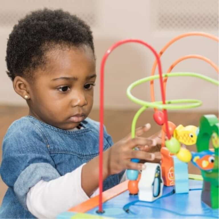 Bright young girl playing with colourful shape sorting toy at Thrive Childcare, promoting early learning and child development.
