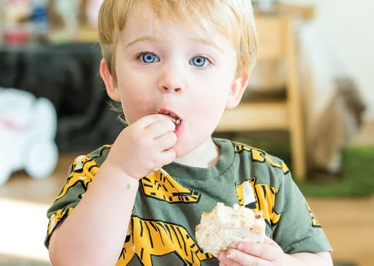 Bright young boy enjoying a snack during outdoor play at Thrive Childcare, showcasing a fun and engaging preschool environment for early childhood development.