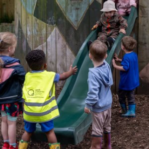 Young children playing on a slide at Thrive Childcare outdoor playground, promoting early childhood development and outdoor fun.