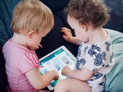 Two young children engaging with a tablet in a colourful childcare setting, promoting early childhood education and learning at Thrive Childcare.